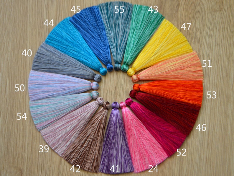 May include: A circle of colorful silk tassels with numbers from 24 to 55. The tassels are arranged in a circle on a wooden surface.