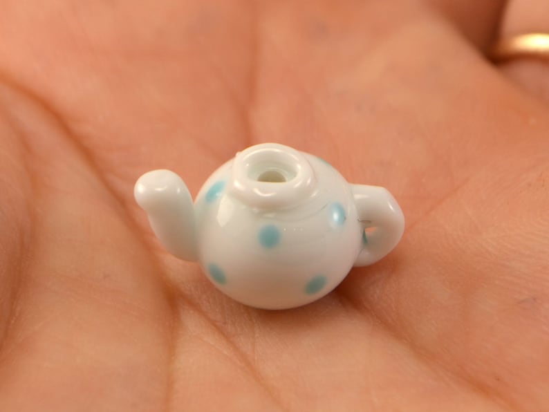 Puede incluir: Una tetera blanca peque&ntilde;a con lunares azules. La tetera tiene un pico y una asa.