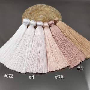 May include: Six different shades of white and pink tassels, from white to light pink to brown. The tassels are arranged in a row from left to right, with the lightest shade on the left and the darkest shade on the right. The tassels are labeled with numbers: #0, #32, #4, #78, #5, and #80.