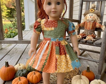 May include: A doll with auburn hair styled in a ponytail, wearing a patchwork dress featuring green, orange, and yellow floral and polka dot patterns with short puff sleeves. The doll has brown eyes and is wearing simple brown flat shoes.