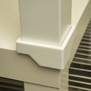 Può includere: Primo piano di un'unità a scaffale bianca con una base in plastica bianca. La base ha una forma quadrata con bordi arrotondati.