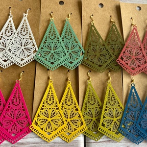 May include: Assortment of eight pairs of dangle earrings. Each pair features a triangular, laser-cut design with intricate floral patterns. The earrings are available in a variety of colours, including white, green, brown, pink, yellow, and blue.