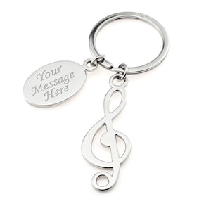 May include: Silver-toned metal keychain with a treble clef charm and a small oval tag that says "Your Message Here".