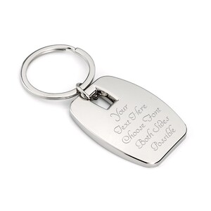 May include: Silver metal keychain with a rectangular tag. The tag has an engraved message that says "Your Text Here Choose Font Both Sides Possible".