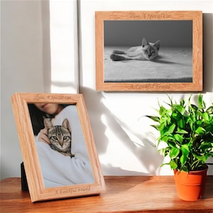May include: Two wooden picture frames, each containing a cat photo. The top frame features a black and white image of a cat lying down, while the bottom frame shows a colour photo of a cat being held by a person. Both frames are engraved with the text "Luna, A Special Cat" and "A Faithful Friend".