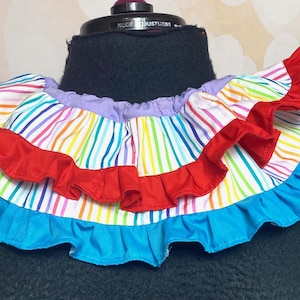 May include: A colourful rainbow striped fabric collar with red and blue ruffles. The collar is made of cotton and is perfect for adding a touch of whimsy to any outfit.