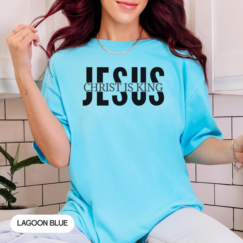 A woman wearing a blue t-shirt with the text "JESUS IS KING" printed on it.