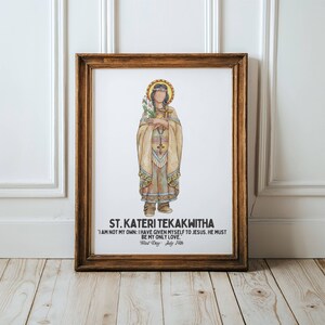 May include: A framed print featuring a watercolor illustration of St. Kateri Tekakwitha. The artwork depicts a figure in traditional Native American attire, holding a cross and flowers, with a halo. Text at the bottom reads "ST. KATERI TEKAKWITHA".