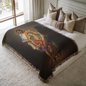 May include: A woven throw blanket featuring a dark background with a central illustration of a figure in a white and blue garment holding a green-cloaked figure who carries a large bouquet of red and orange flowers, finished with fringed edges.