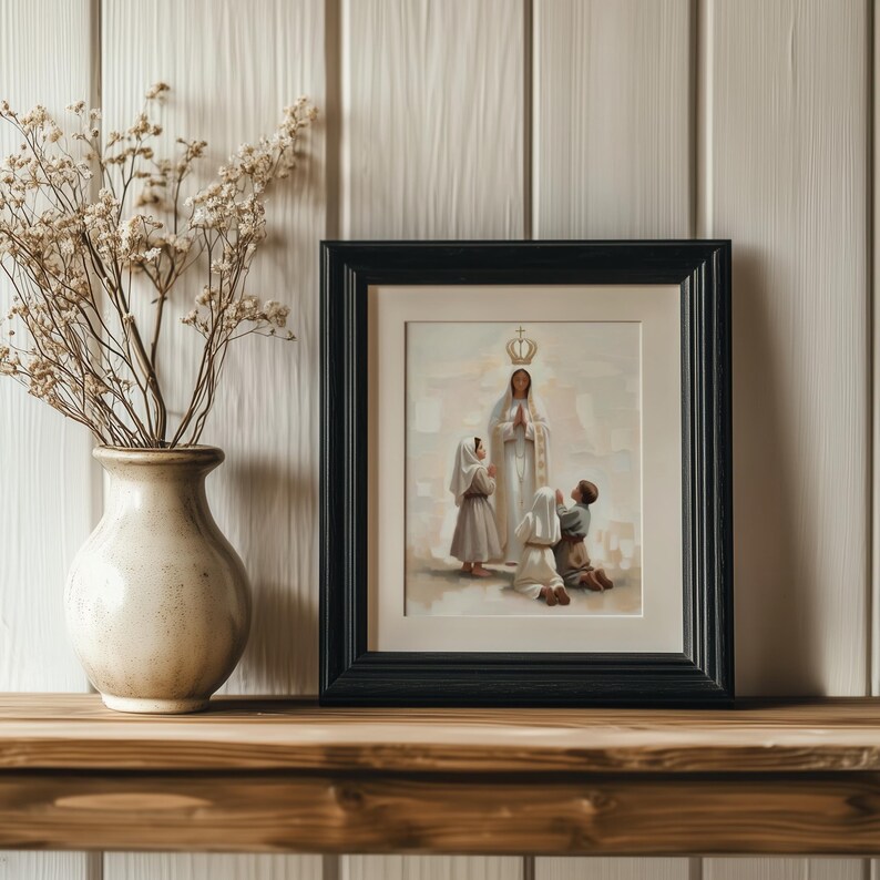 May include: A framed religious print depicts a woman in a white robe and crown, with children kneeling before her. The artwork is in a black frame, set on a wooden shelf, with a vase of dried flowers to the left.