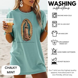 May include: A chalky mint t-shirt with an image of the Virgin Mary and the text "pray like a mom." Washing instructions are shown on the right. The t-shirt is made of high-quality apparel.