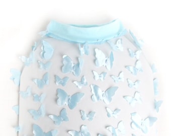 May include: A light blue dog shirt with a sheer overlay featuring a pattern of light blue butterflies. The shirt has a crew neck and is made of a soft, comfortable material. The text "IceCreamTree Studio" is printed on the bottom of the shirt.