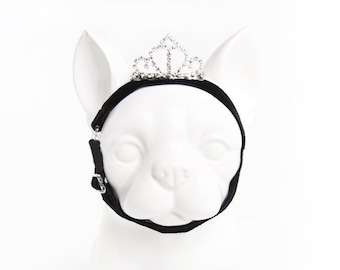 May include: A white dog head mannequin wearing a black velvet dog harness with a silver rhinestone tiara.