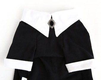 May include: Black and white pet dress with a white collar and a black and silver brooch. The dress has white cuffs and the text "Icecreamtrie Studio" is printed on the bottom.