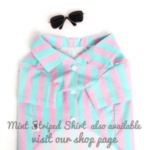 Puede incluir: Una camisa a rayas rosa y menta con cuello y botones. La camisa est&aacute; hecha para una mascota y tiene mangas cortas.  "Mint Striped Shirt also available visit our shop page" est&aacute; escrito en la parte inferior de la imagen.