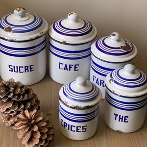 Puede incluir: Conjunto de cinco botes vintage de esmalte blanco con rayas azules y tapas. Los botes están etiquetados con "Sucre", "Café", "Farina", "Especias" y "Té".