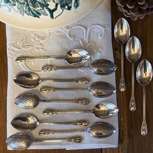 May include: A white ceramic mug with a black handle and the text "But First, Coffee" in a bold, black font. The mug is set against a blurred background, suggesting a cozy setting.