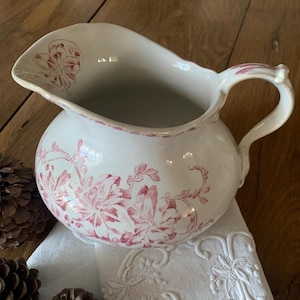 May include: White ceramic jug with a pink floral design. The jug has a wide mouth and a handle.