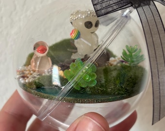 Diorama alienígena diminuto y brillante con adorno transparente. Terrario en miniatura de otro mundo que brilla en la oscuridad. Río de gemas, puentecito y pato.