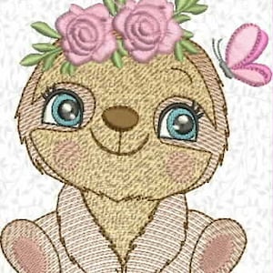 Pode incluir: Um bicho-preguiça bordado com uma coroa de flores e uma borboleta. O bicho-preguiça tem olhos grandes azuis, um nariz castanho e uma expressão sorridente. A coroa de flores apresenta rosas cor-de-rosa e folhas verdes. Uma borboleta rosa está à direita do bicho-preguiça.