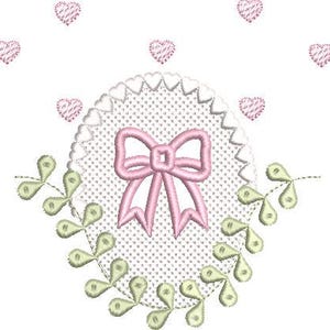 May include: An embroidered design featuring a pink bow, surrounded by a white dotted circle with a scalloped edge. Green and yellow leaf-like shapes and pink hearts are scattered around the design on a white background.