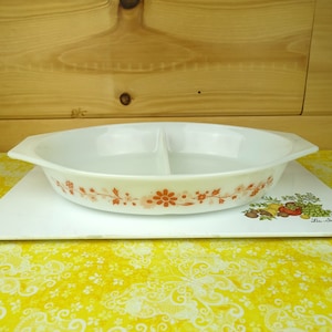 May include: White divided casserole dish with a floral pattern in shades of orange and pink. The dish has a scalloped edge and two handles.