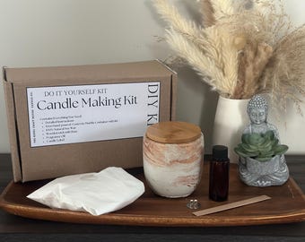 May include: A DIY candle making kit with a brown cardboard box that says "Do It Yourself Kit Candle Making Kit" and a white concrete candle jar with a wooden lid. The kit also includes a small bag of soy wax, a wooden wick, a bottle of fragrance oil, and a candle label.