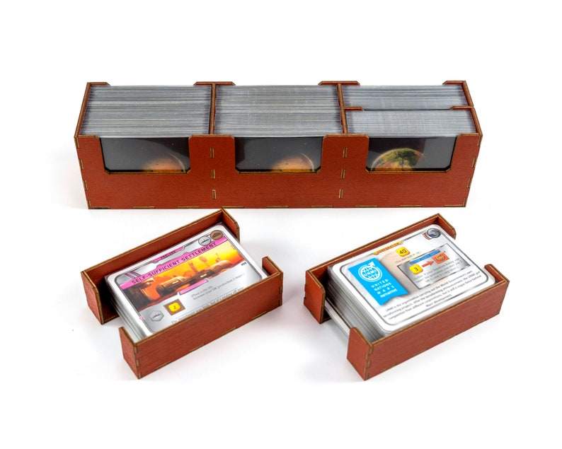May include: A brown wooden organiser with three compartments for storing cards. The organiser has clear plastic windows to view the cards. Two smaller brown wooden trays are also shown, each holding a stack of cards.