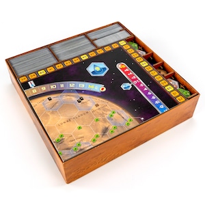 May include: A wooden game organiser with compartments for storing game pieces and cards. The organiser features a printed image of a planet with a hexagonal grid and the text "LUNAE PLANUM".