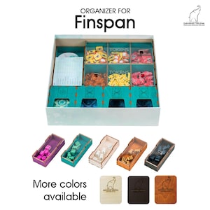 Könnte beinhalten: Ein türkisfarbener und weißer Organizer für das Brettspiel "Finspan" von Gaming Trunk. Der Organizer verfügt über mehrere Fächer zur Aufbewahrung von Spielkomponenten, darunter Token. Der Organizer ist in verschiedenen Farben erhältlich, darunter Lila, Türkis, Naturholz, Braun und Schwarz.