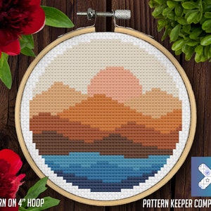 May include: A cross-stitch pattern of a sunset over a mountain range with a lake in the foreground. The pattern is in a 4-inch hoop and is compatible with Pattern Keeper.