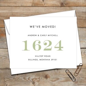 May include: A white announcement card with the text "WE'VE MOVED!" in black. Below, the names "ANDREW & CARLY MITCHELL" are printed. The address "1624 HILLTOP ROAD BILLINGS, MONTANA 59101" is also displayed in a soft green color.