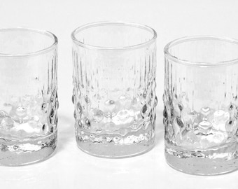 Peut inclure: Quatre verres à shot en verre transparent avec un motif texturé en forme de bulles.