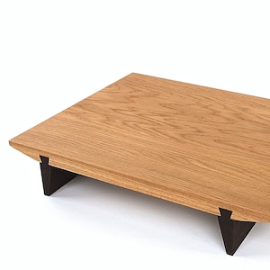 Puede incluir: Una mesa de centro rectangular de madera con una tapa de madera marrón claro y patas triangulares negras.