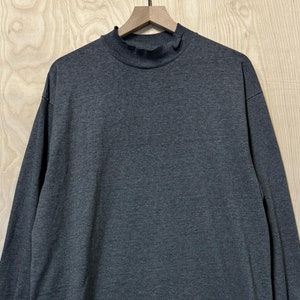 May include: A dark gray long-sleeved shirt with a mock neck.