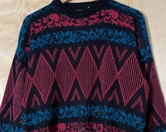 Jersey de punto acrílico con cuello redondo y rayas abstractas negras, rojas y azules de la marca Vintage Mathias, talla M.