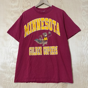 May include: A maroon short-sleeved t-shirt featuring the text MINNESOTA in yellow arched lettering above a graphic of a gopher mascot wearing a maroon and gold jersey, with the text GOLDEN GOPHERS printed in yellow below the mascot graphic.
