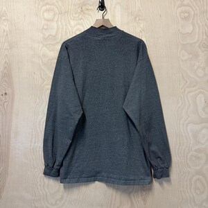 May include: A long-sleeved, dark gray t-shirt with a mock neck.