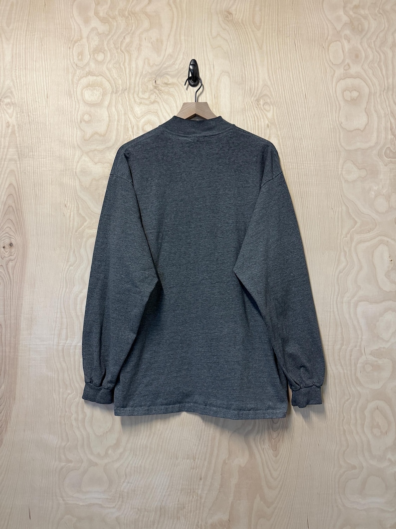 May include: A long-sleeved, dark gray t-shirt with a mock neck.