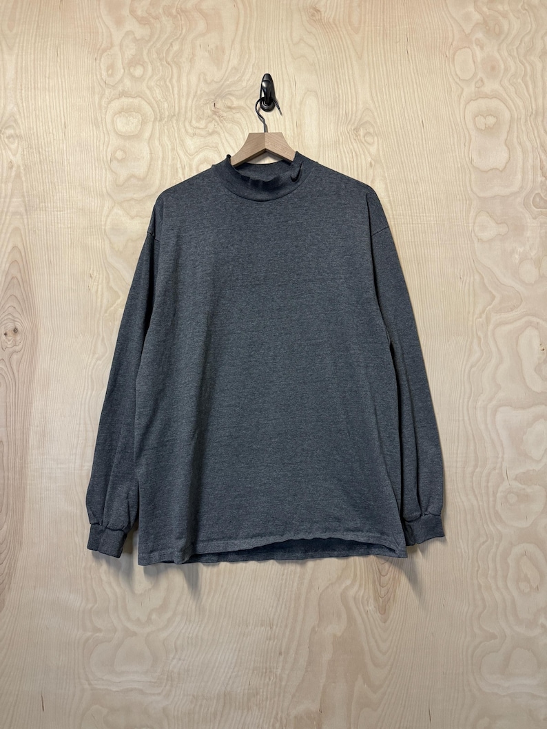 May include: A dark gray long-sleeved shirt with a mock neck.