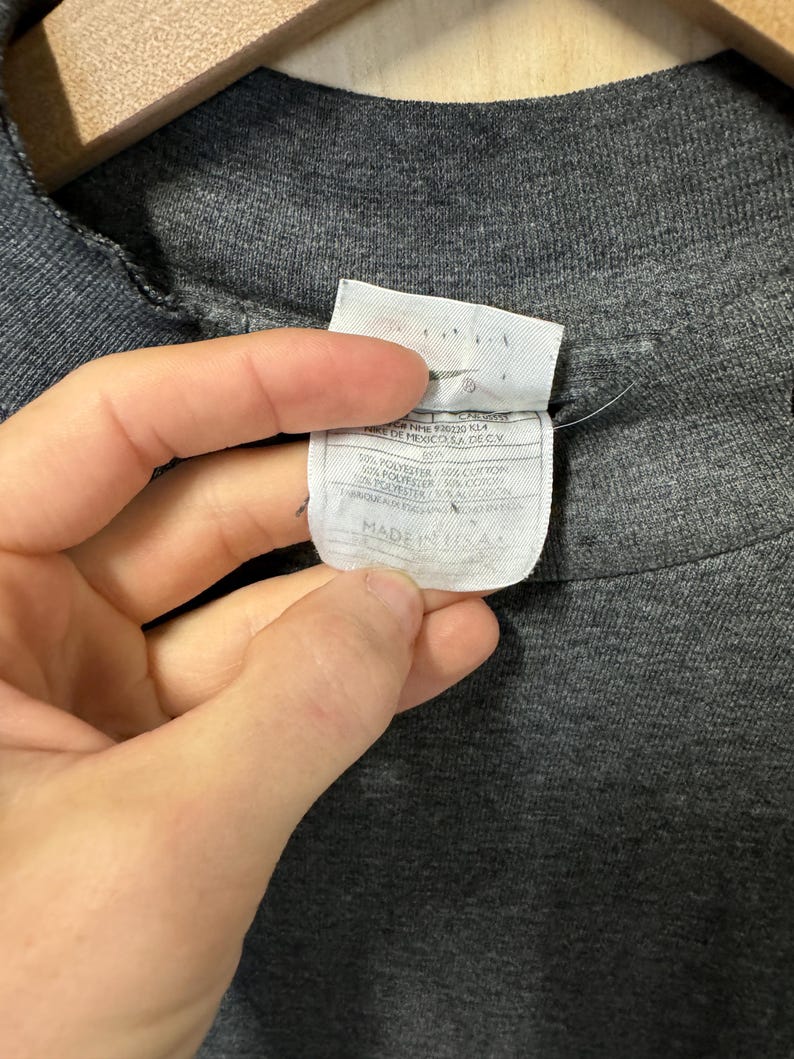 May include: A gray t-shirt with a white tag that reads "100% polyester / 50% cotton / 50% polyester / 50% cotton Made in Mexico, S.A. de C.V."