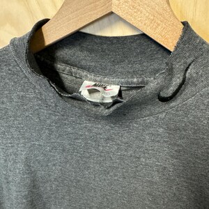 May include: A gray mock neck t-shirt with a Nike logo tag. The shirt is made of a soft, comfortable material.