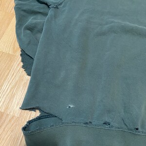 May include: A dark green sweatshirt with a distressed look. The sweatshirt has several small holes and frayed edges.