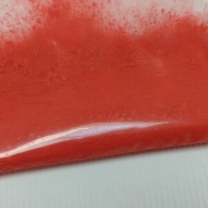 May include: A close-up of a small plastic bag filled with bright orange powder.