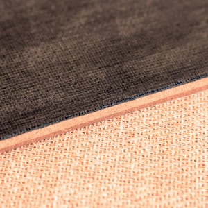 May include: Close-up of a dark brown fabric with a textured surface. The fabric is layered over a light brown fabric with a woven texture.