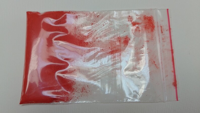 May include: A small plastic bag filled with a bright red powder. The bag is sealed with a zipper.
