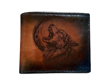 May include: A brown bi-fold wallet featuring a dark, engraved illustration of a wolf howling at a crescent moon. The leather surface displays a gradient of deep brown and black tones, with detailed linework defining the wolf's fur and teeth.