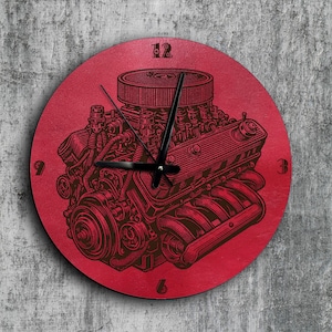 May include: Red round clock with a black engine design and black clock hands. The clock face has black numbers 12, 9, 3, and 6.