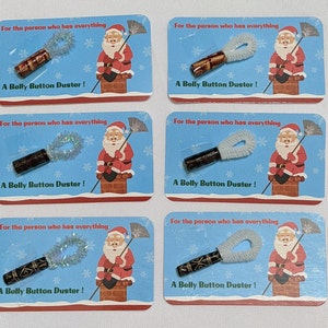 May include: Six Christmas gift tags featuring a cartoon Santa Claus sitting on a chimney. Each tag has a small wooden belly button duster with a white feather and the text "For the person who has everything" and "A Belly Button Duster!"