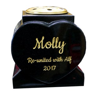 May include: Black heart-shaped granite pet memorial with a gold inscription that reads "Molly Re-united with Alf 2017".